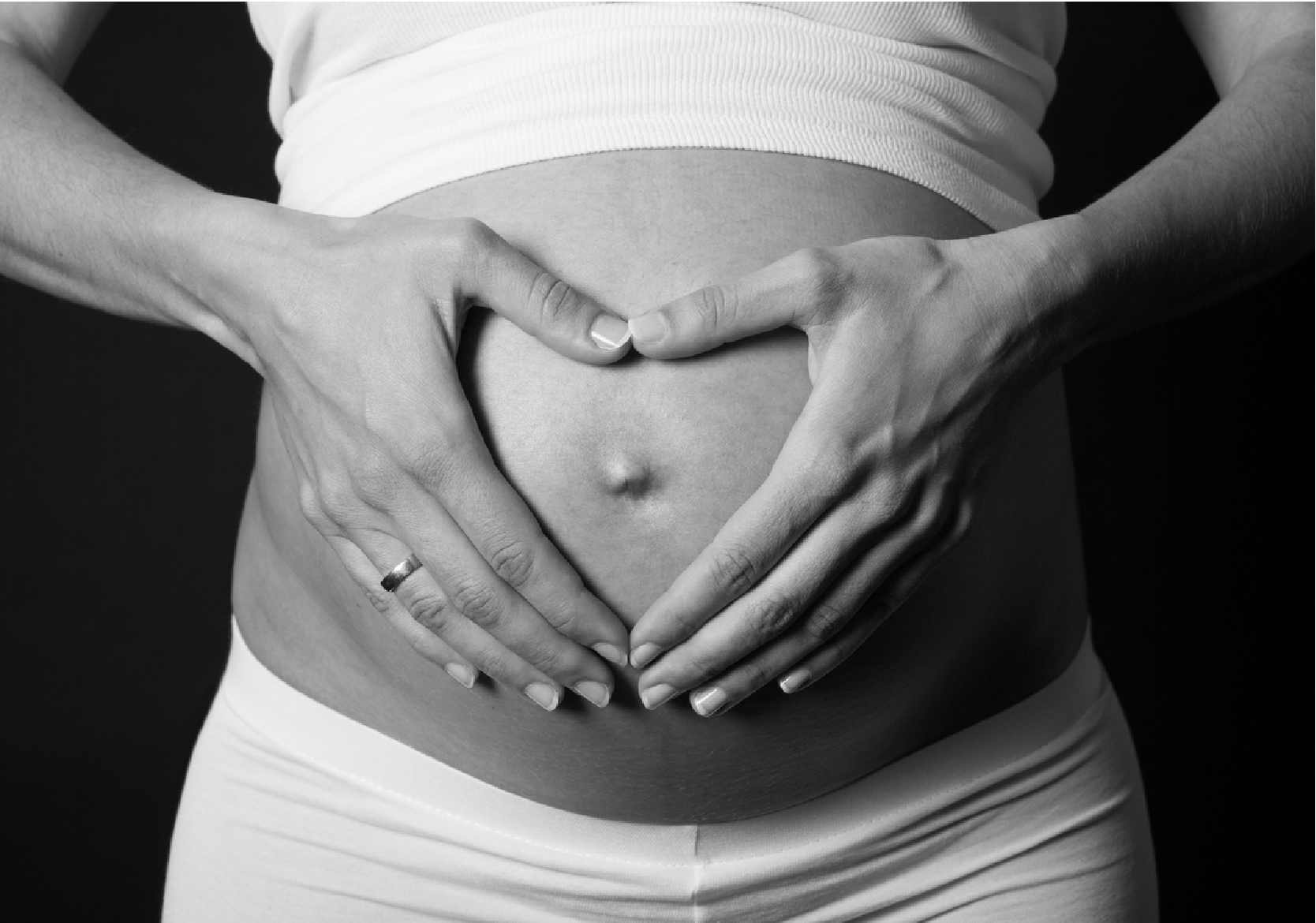A pregnant woman with her hands on her stomach. 